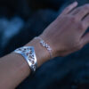 a silver leaf bracelet with delicate leaf details is worn on an arm