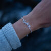 a silver leaf bracelet with delicate leaf details is worn on an arm
