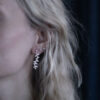 A woman wearing a pair of silver leaf earrings inspired by delicate branches andlkeaves
