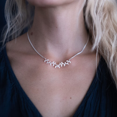 A woman wearing a delicate silver leaf necklace