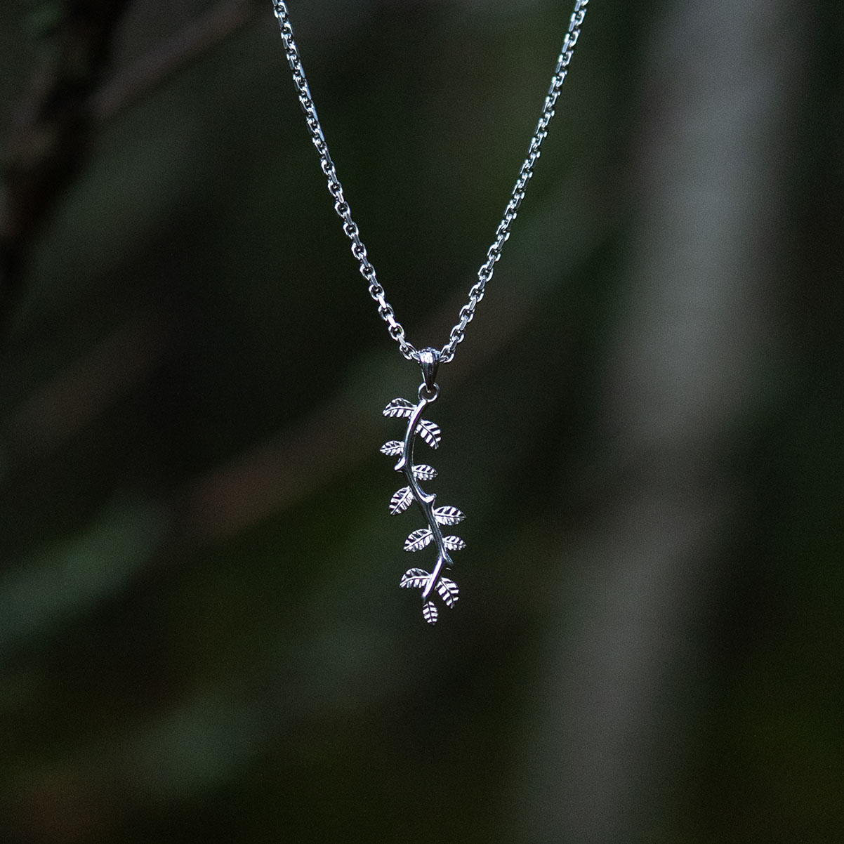 Close up of a silver leaf pendant necklace with delicate botanical details